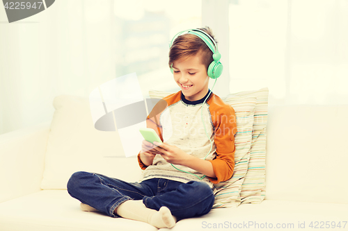 Image of happy boy with smartphone and headphones at home