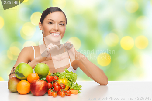 Image of woman with fruits and vegetables showing heart