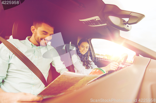 Image of happy man and woman with road map driving in car