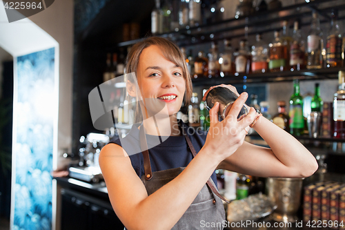 Image of barmaid with shaker preparing cocktail at bar