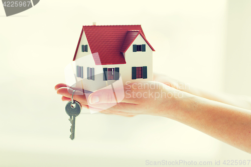 Image of close up of hands holding house model and keys