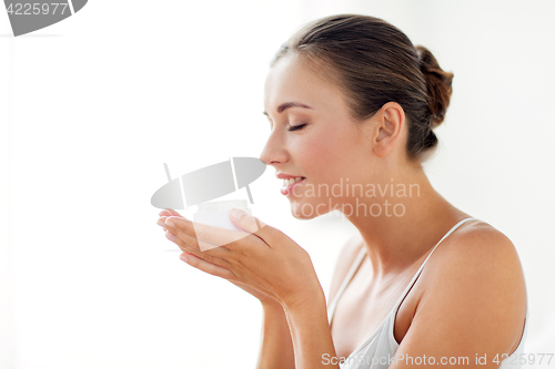 Image of close up of happy woman holding and smelling cream