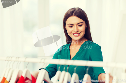 Image of happy woman choosing clothes at home wardrobe