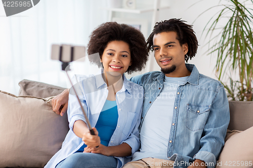 Image of happy couple with smartphone taking selfie at home