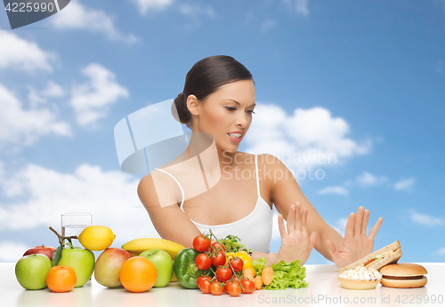 Image of woman with fruits rejecting fast food