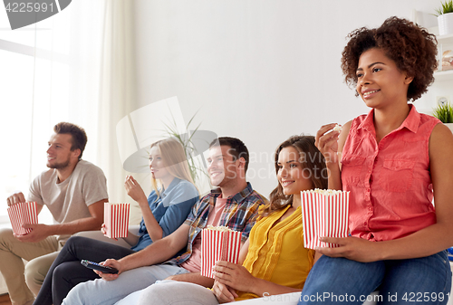 Image of happy friends with popcorn watching tv at home