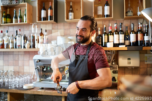 Image of barista with holder and tamper making at coffee