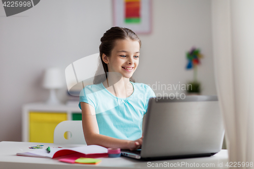 Image of happy girl typing on laptop at home