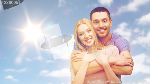 Image of happy smiling couple hugging over sky and sun