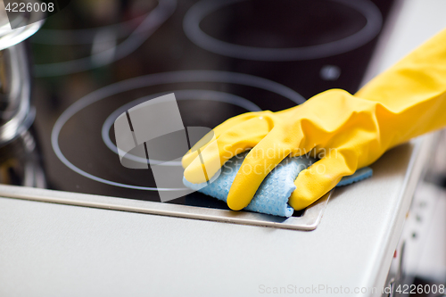 Image of hand with rag cleaning cooker at home kitchen