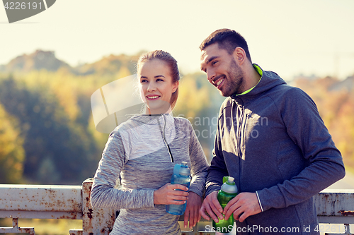 Image of smiling couple with bottles of water outdoors