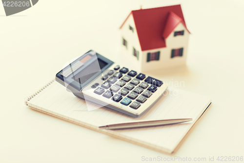 Image of close up of home model, calculator and notebook