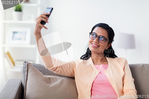 Image of happy woman taking selfie with smartphone at home