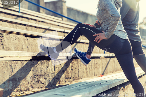 Image of close up of couple stretching leg on stadium