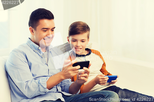 Image of happy father and son with smartphones at home