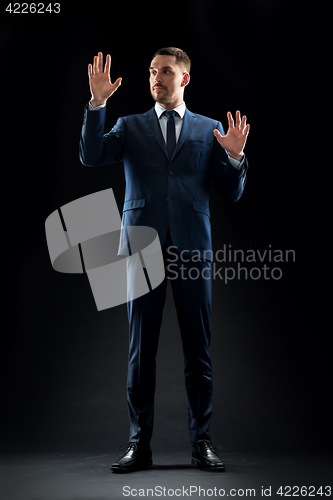 Image of businessman in suit touching something invisible