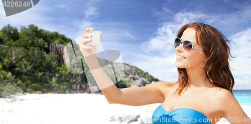 Image of woman in swimsuit taking selfie with smatphone