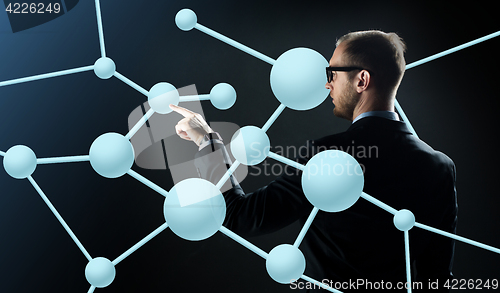 Image of businessman pointing finger to virtual molecule