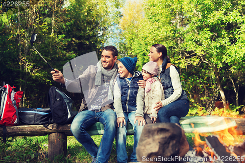 Image of family with smartphone taking selfie near campfire