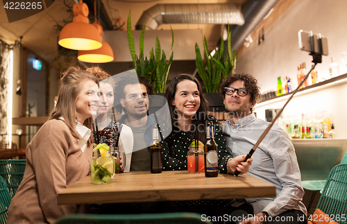 Image of friends taking selfie by smartphone at bar or cafe