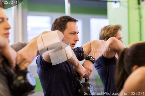 Image of group of people with kettlebells exercising in gym