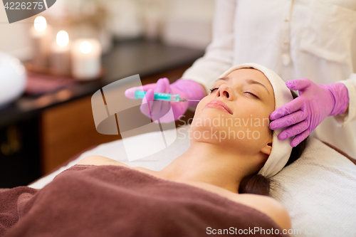 Image of beautician doing beauty injection to woman lips