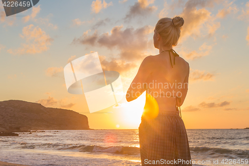 Image of Woman practicing yoga on sea beach at sunset.