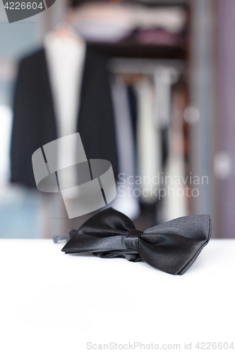 Image of Bow tie. Open closet and tuxedo. 
