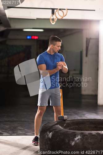 Image of man workout with hammer and tractor tire