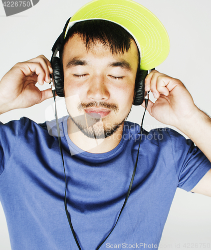 Image of young asian man in hat and headphones listening music on white b