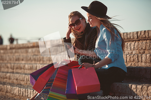 Image of Two girls walking with shopping on city streets