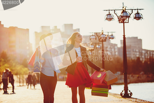 Image of Two girls walking with shopping on city streets