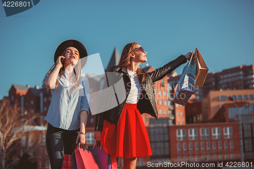 Image of Two girls walking with shopping on city streets