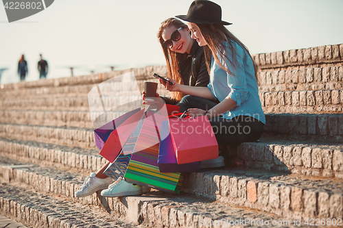 Image of Two girls walking with shopping on city streets