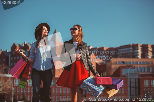 Image of Two girls walking with shopping on city streets