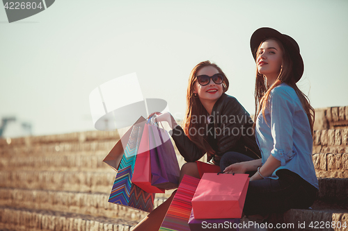 Image of Two girls walking with shopping on city streets