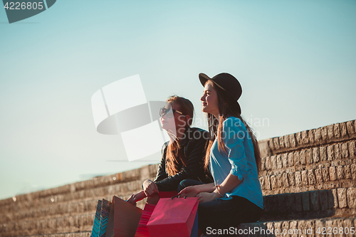 Image of Two girls walking with shopping on city streets