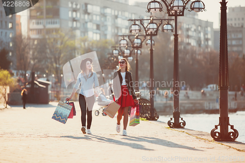 Image of Two girls walking with shopping on city streets