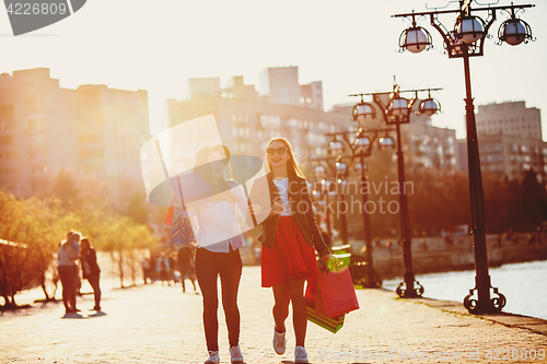 Image of Two girls walking with shopping on city streets
