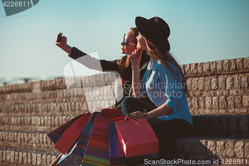 Image of Two girls walking with shopping on city streets