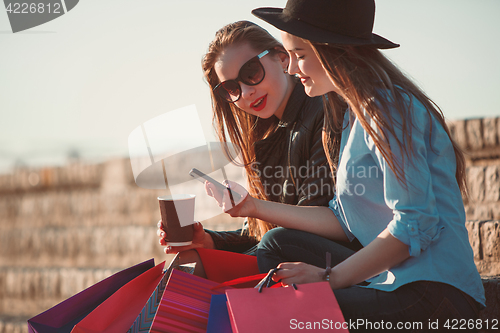 Image of Two girls walking with shopping on city streets