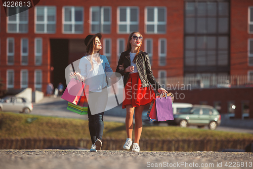 Image of Two girls walking with shopping on city streets