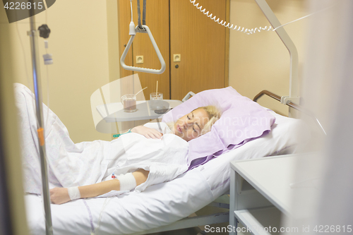 Image of Bedridden female patient recovering after surgery in hospital care.