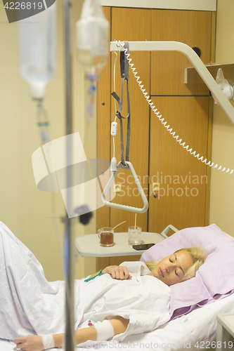 Image of Bedridden female patient recovering after surgery in hospital care.