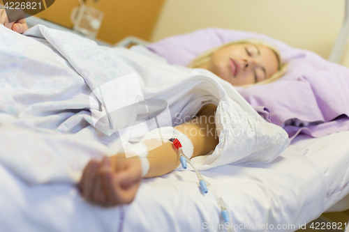 Image of Bedridden female patient recovering after surgery in hospital care.