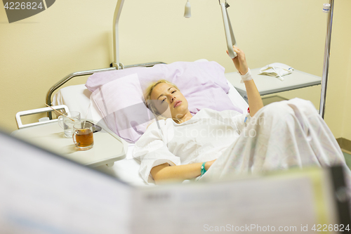 Image of Bedridden female patient recovering after surgery in hospital care.