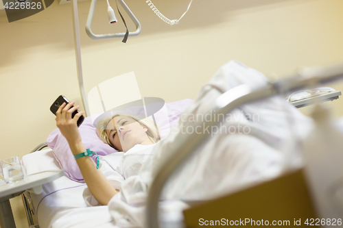 Image of Bedridden female patient recovering after surgery in hospital care.