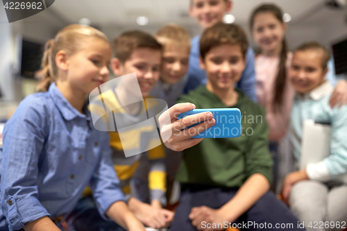 Image of group of happy kids taking selfie with smartphone