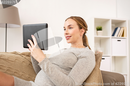 Image of happy pregnant woman with tablet pc at home