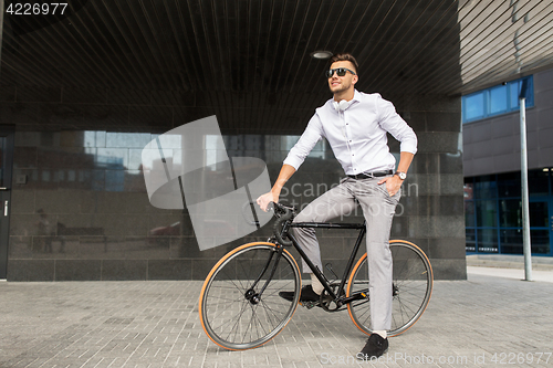 Image of man with bicycle and headphones on city street